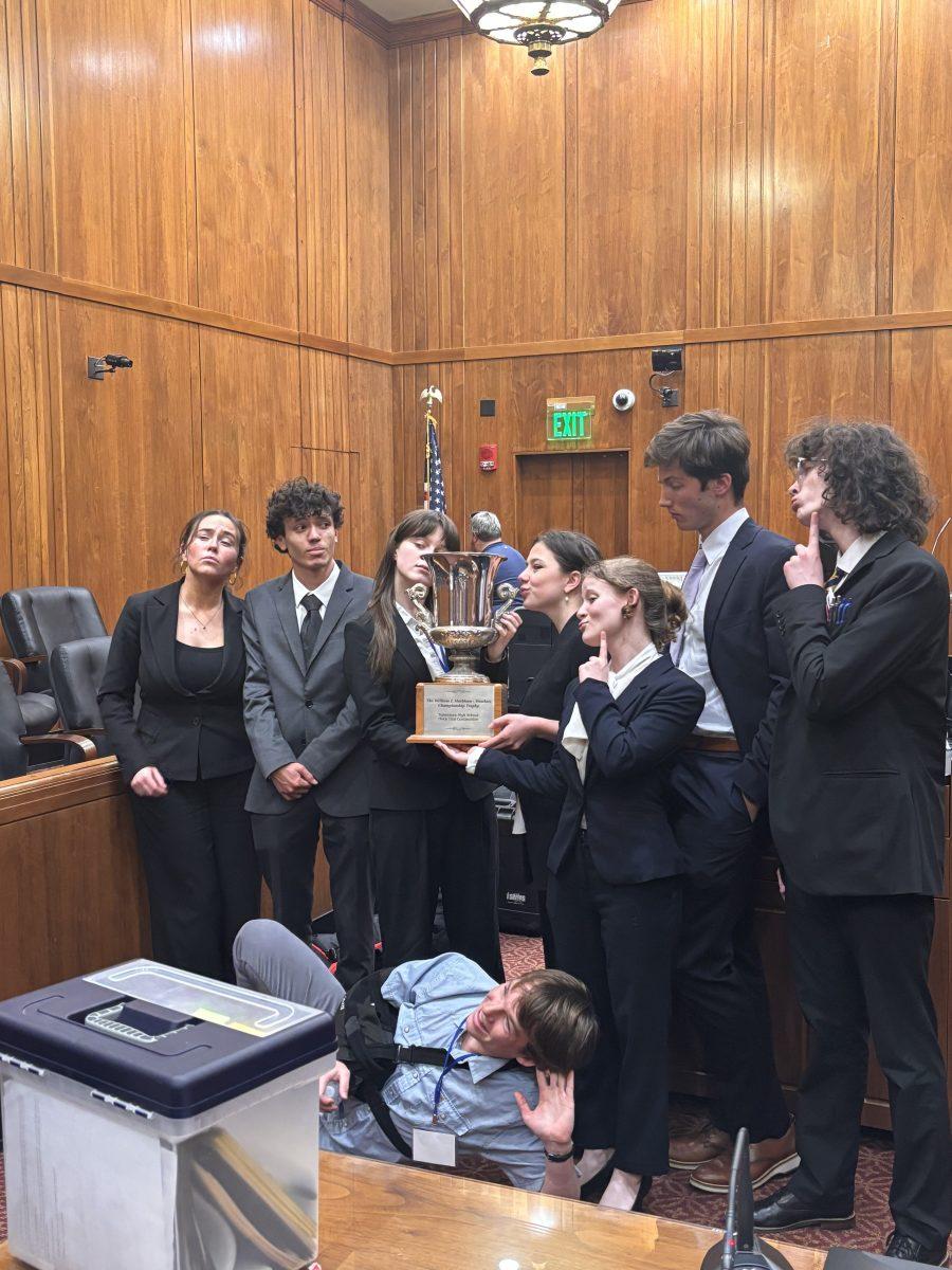 Clockwise from left: Caroline Quinones '24, Xavier Warren '24, Erin Joyce '25, Margot Ross '25, Ophelia Cherry-Pulay '25, Benjamin Kampine '25, Bronson Schmidt '25 and Henry Gatto '25 -- celebrate with their state championship trophy (via Wilson Hubbell).