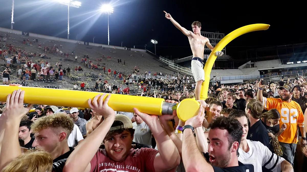 A Vanderbilt fan stands triumphantly on top of the goalpost. (via Matthew Maxey/Icon Sportswire)