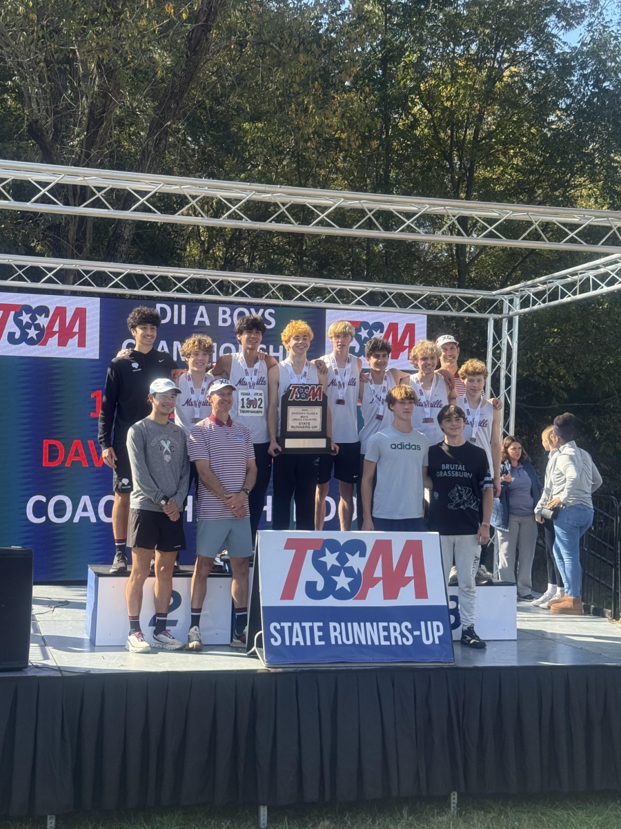 The boys’ team poses on the podium with the 2025 State runner-up plaque. (via Lindsey Bachman)